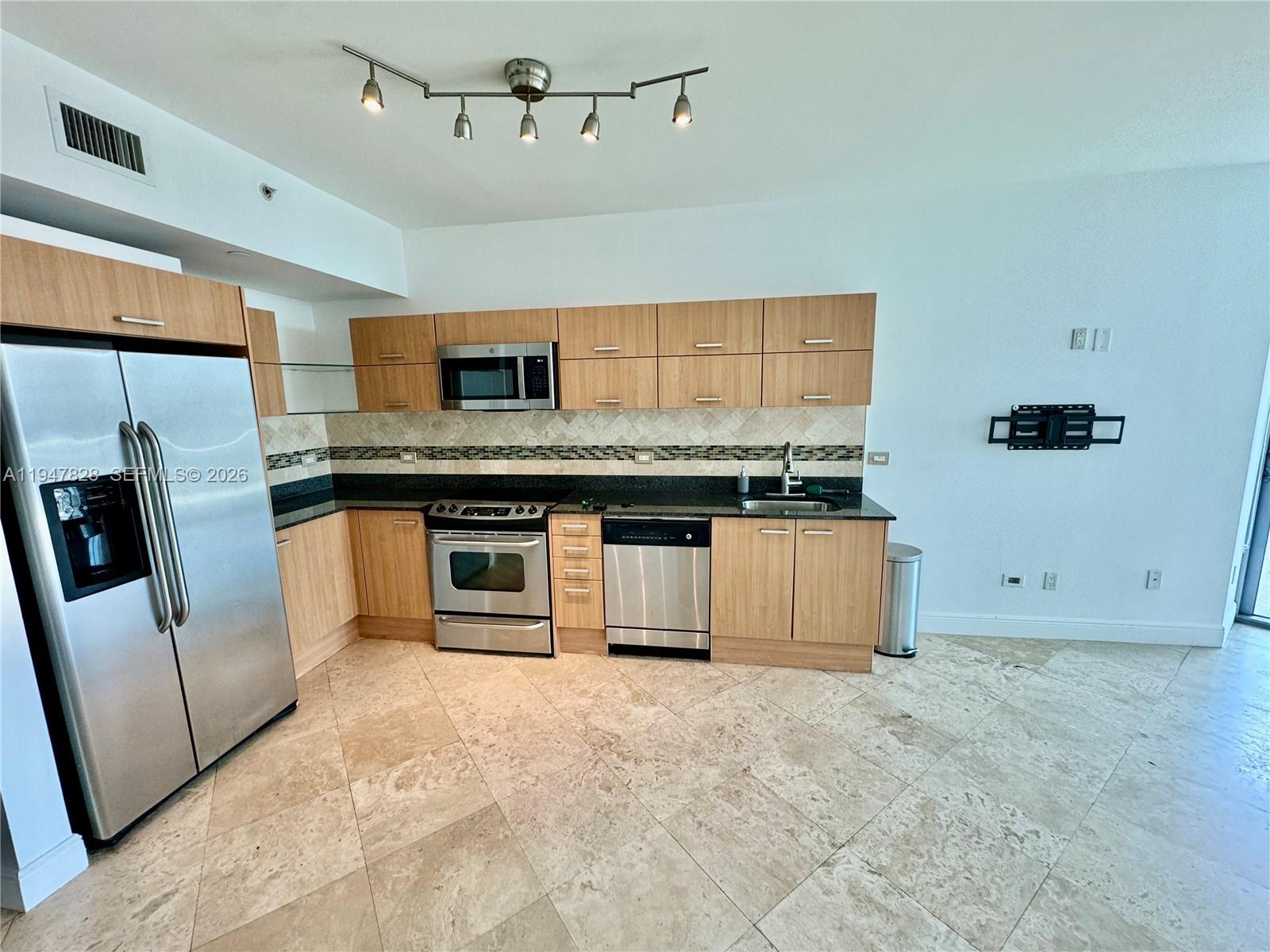 A kitchen features light wood cabinets, stainless steel appliances, dark countertops, and tile flooring — 350 S Miami Ave # 2912, Miami FL 33130, MIAMI, FL