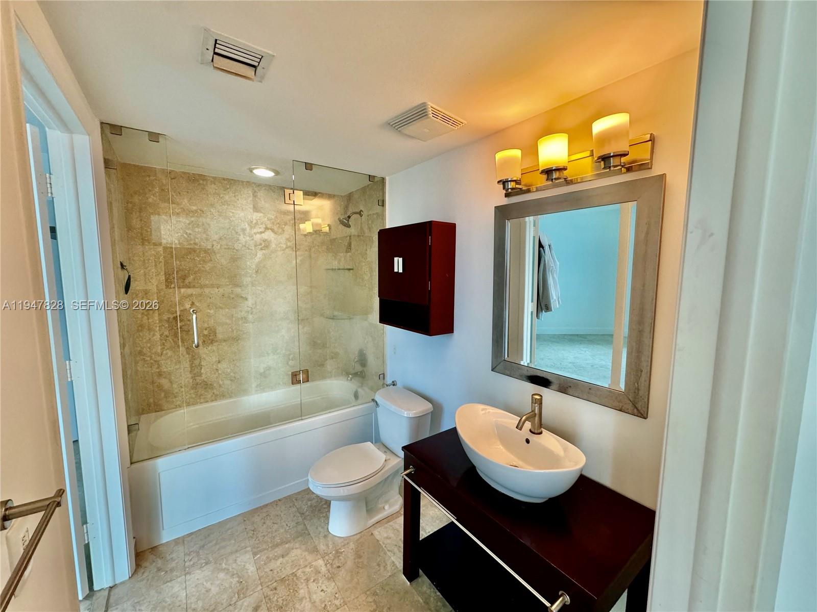 A bathroom features a glass-enclosed tub, a vessel sink vanity, and beige tile flooring — 350 S Miami Ave # 2912, Miami FL 33130, MIAMI, FL