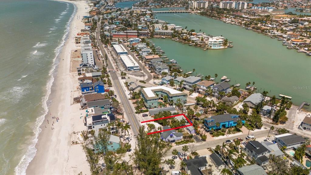 An aerial view shows a coastal neighborhood with a red-outlined vacant lot near the beach — 8403 W GULF BOULEVARD, TREASURE ISLAND, FL