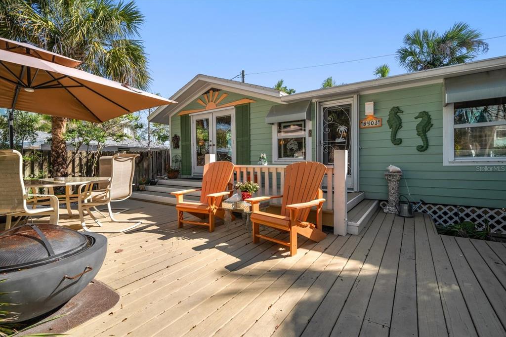 A wooden deck features two orange Adirondack chairs and a fire pit outside a house — 8403 W GULF BOULEVARD, TREASURE ISLAND, FL