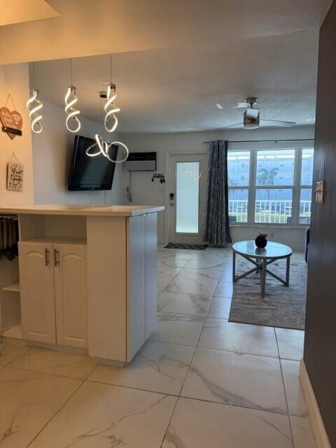 A kitchen island with pendant lights overlooks a living area with tile floors and balcony — 1110 N Riverside Drive # 25, Pompano Beach FL 33062, POMPANO BEACH, FL