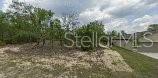A vacant, partially cleared residential lot features scattered trees and sandy ground under a cloudy sky — 3227 W KIRKWOOD PLACE, DUNNELLON, FL