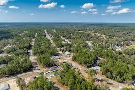An aerial view shows a residential neighborhood with houses nestled among dense trees and roads — 3227 W KIRKWOOD PLACE, DUNNELLON, FL