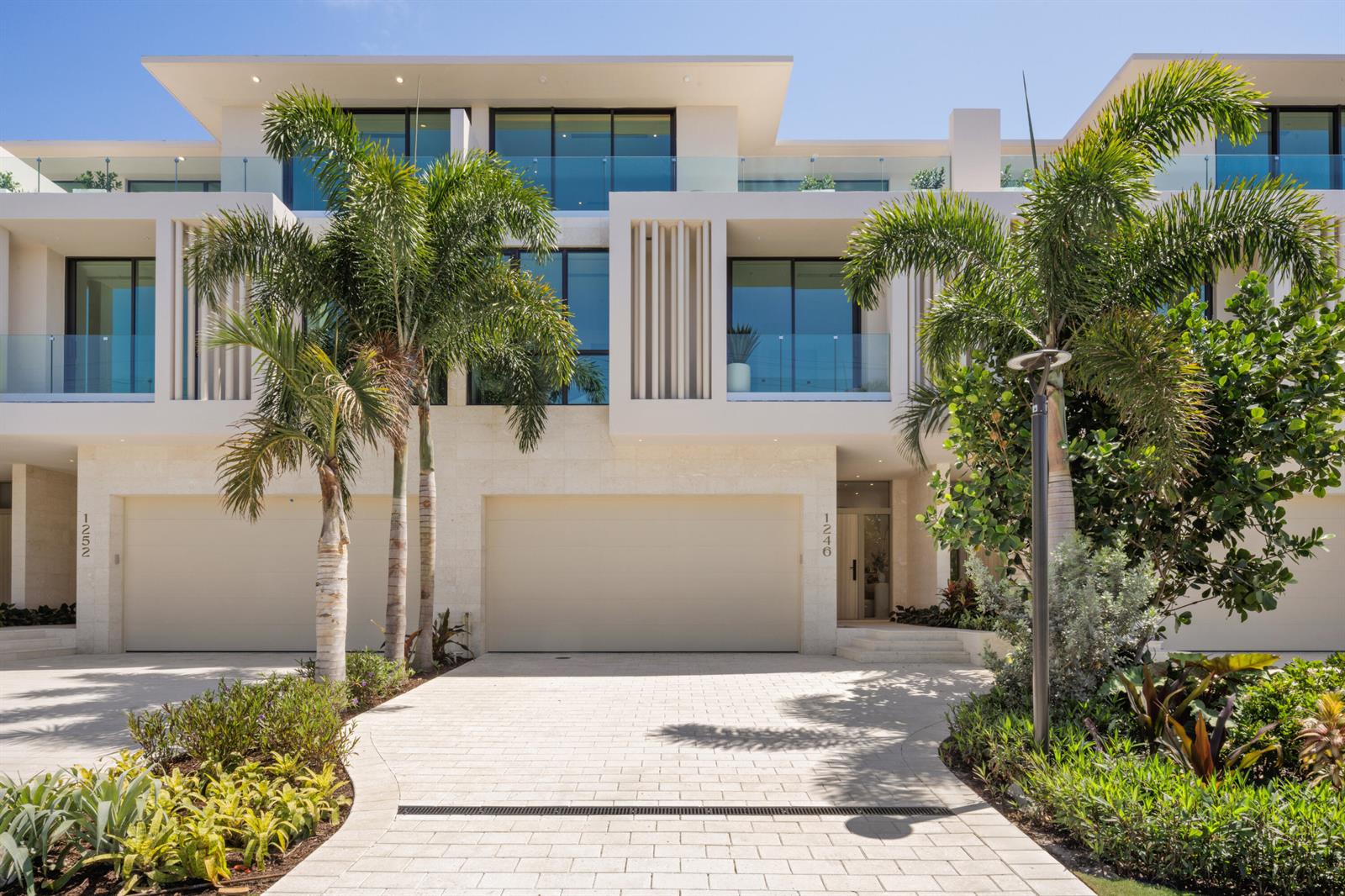 A modern multi-story townhouse exterior with a paved driveway, palm trees, and glass balconies — 1258 George Bush Boulevard, Delray Beach FL 33483, DELRAY BEACH, FL