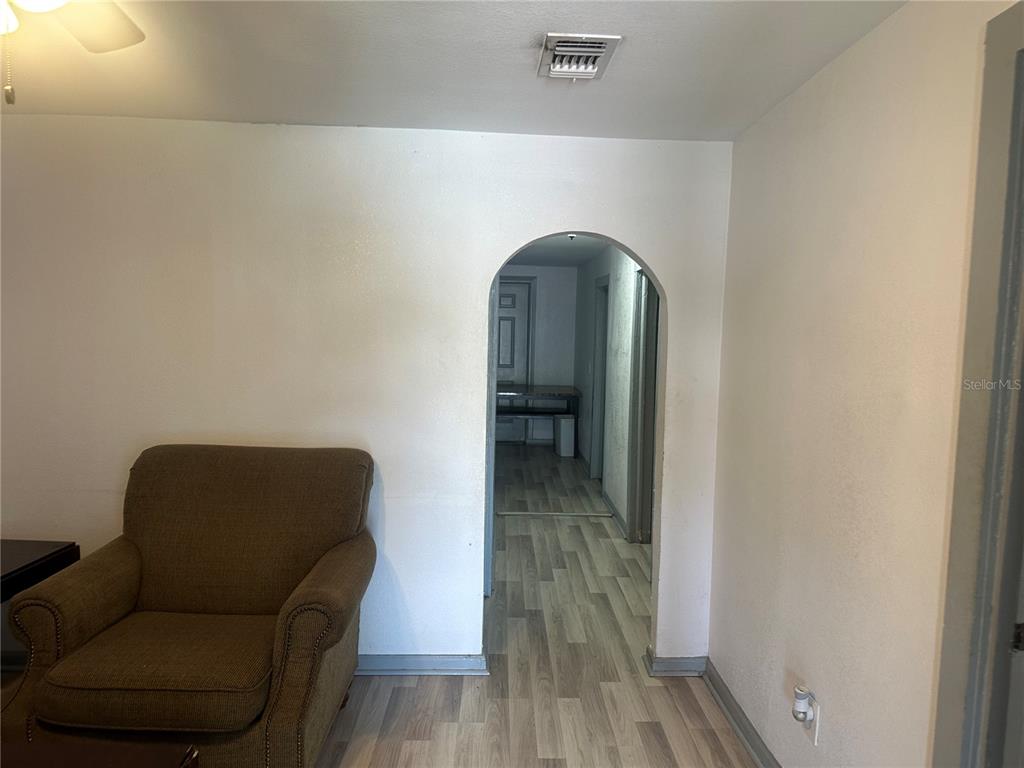 A living room with a brown armchair leads through an arched doorway to a hallway — 4506 N 42ND STREET, TAMPA, FL