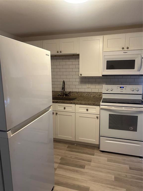 A kitchen features white cabinets, a white refrigerator, a white stove, and a subway tile backsplash — 4506 N 42ND STREET, TAMPA, FL