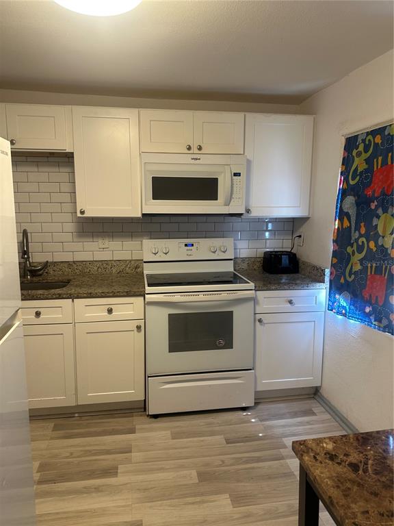 A kitchen with white cabinets, granite countertops, a white stove, and a subway tile backsplash — 4506 N 42ND STREET, TAMPA, FL