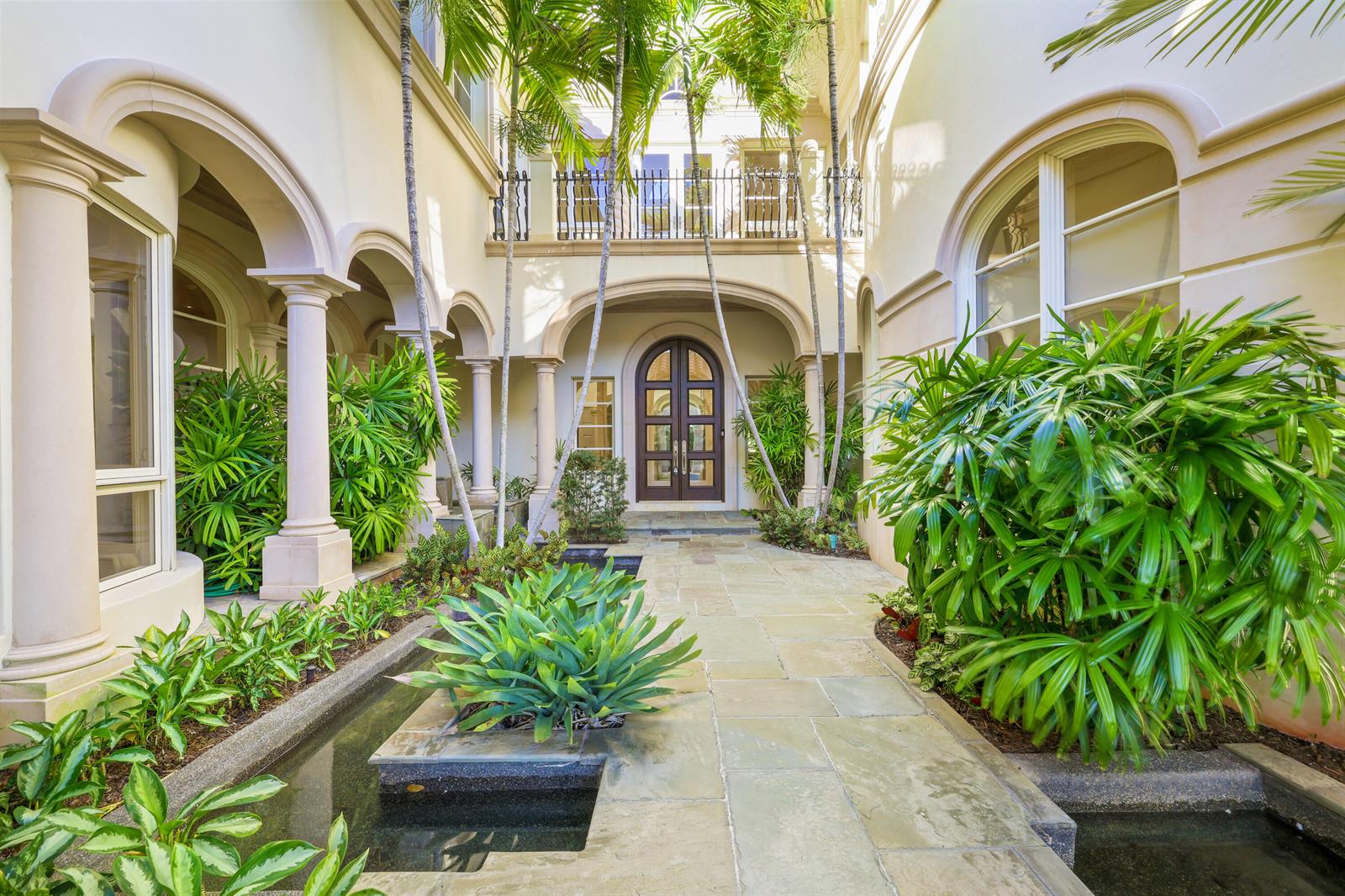 A stone-paved courtyard entrance features a water feature, palm trees, and arched architectural details — 361 Mizner Lake Estates Drive, Boca Raton FL 33432, BOCA RATON, FL