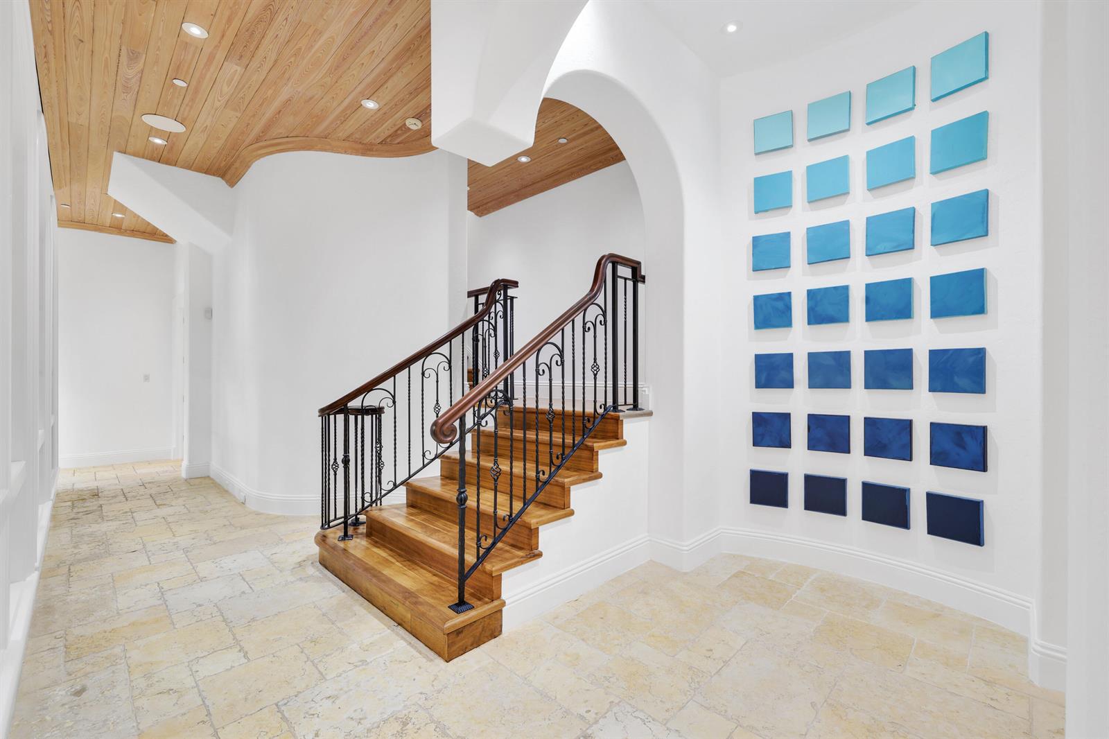 A staircase with a wooden handrail and iron balusters sits in a foyer with tile — 361 Mizner Lake Estates Drive, Boca Raton FL 33432, BOCA RATON, FL