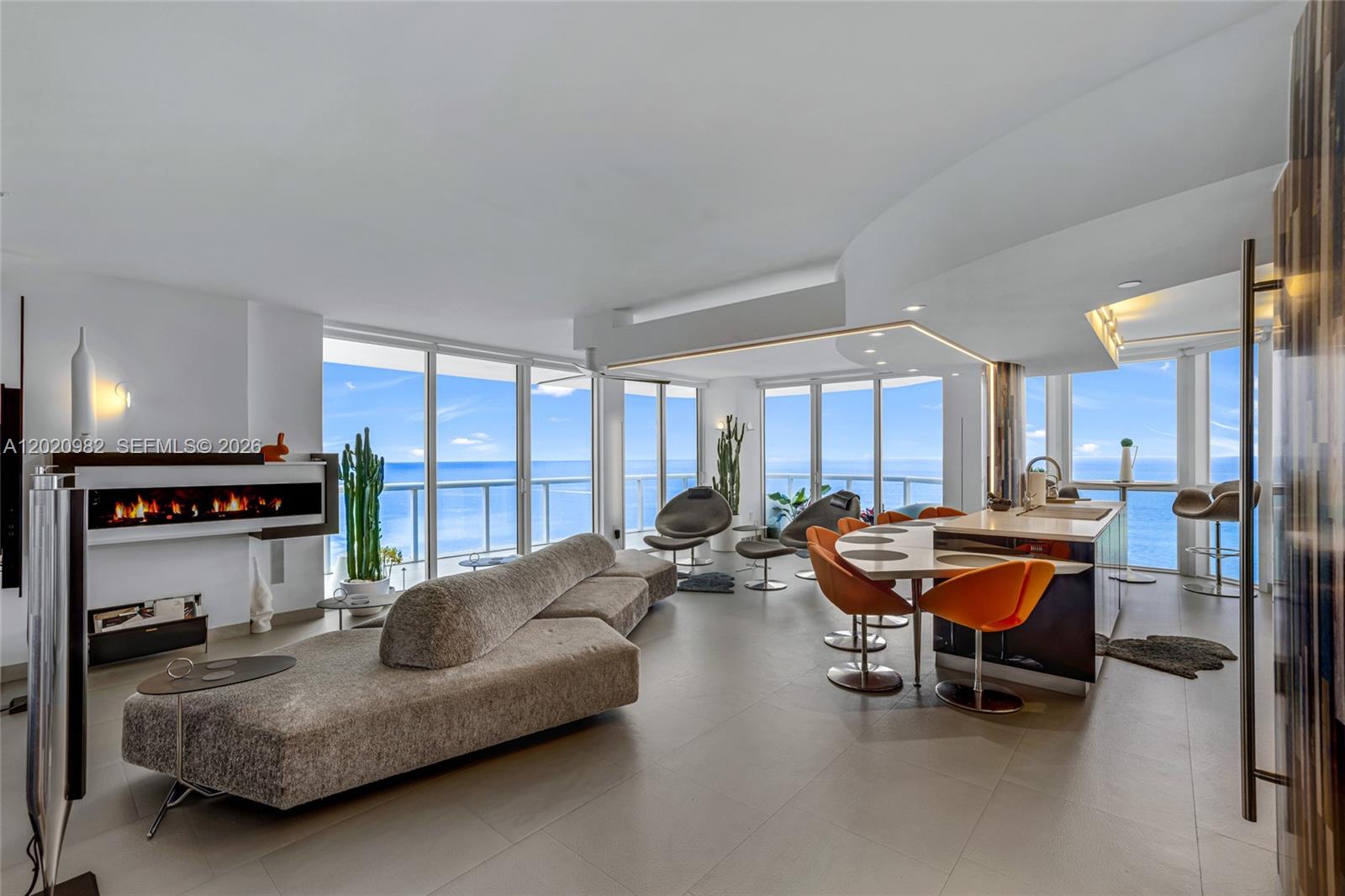 A modern open-concept living area with a fireplace, kitchen island, and floor-to-ceiling ocean views — 6365 Collins Ave # 2301, Miami Beach FL 33141, MIAMI BEACH, FL