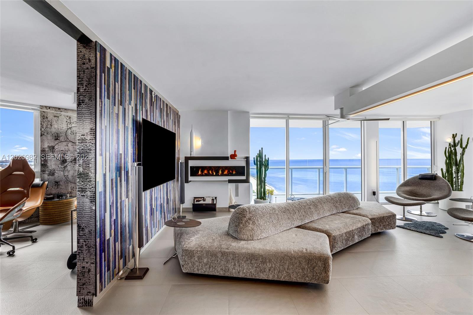 A modern living room features a textured sofa, a fireplace, and floor-to-ceiling ocean views — 6365 Collins Ave # 2301, Miami Beach FL 33141, MIAMI BEACH, FL
