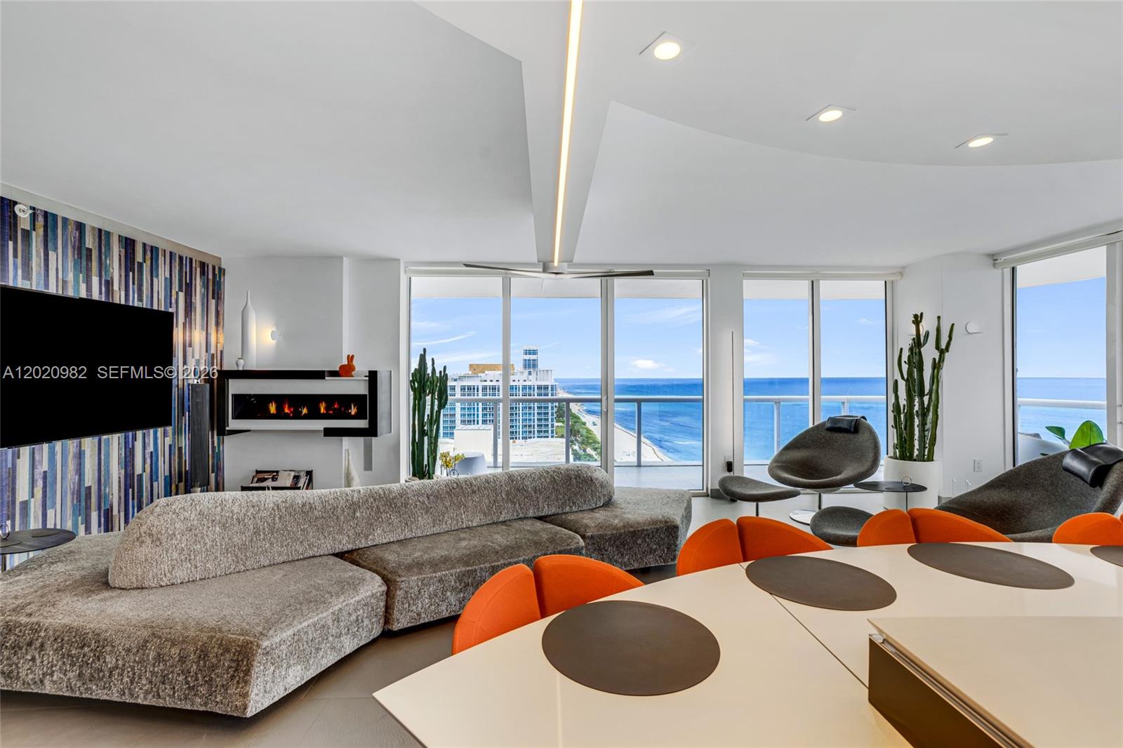 A modern living and dining area features a large sectional sofa, fireplace, and ocean views — 6365 Collins Ave # 2301, Miami Beach FL 33141, MIAMI BEACH, FL