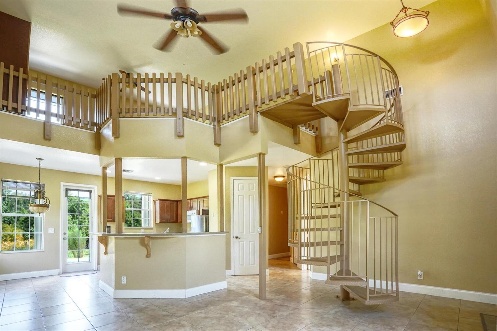 A living room with tile floors, a spiral staircase, and a loft area with wooden railings — 1550 C Road, FL 33470, FL
