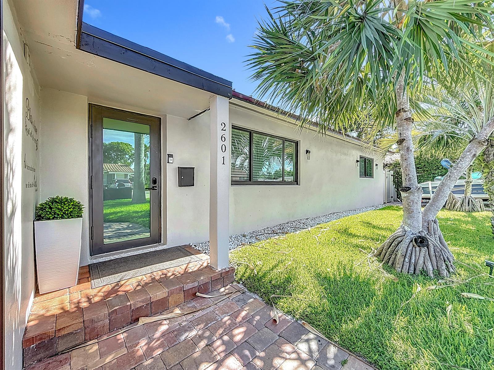 A front entrance with a glass door, brick steps, and a palm tree on a lawn — 2601 NE 18th Street, Pompano Beach FL 33062, POMPANO BEACH, FL