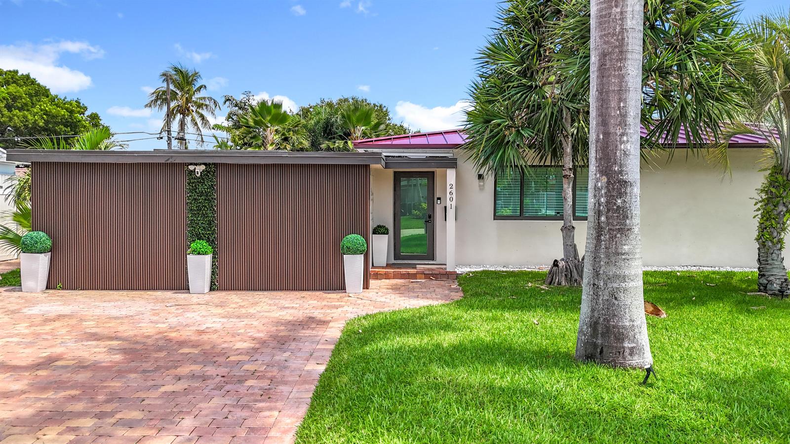 A single-story house with a brown slatted facade, brick driveway, and a green lawn — 2601 NE 18th Street, Pompano Beach FL 33062, POMPANO BEACH, FL
