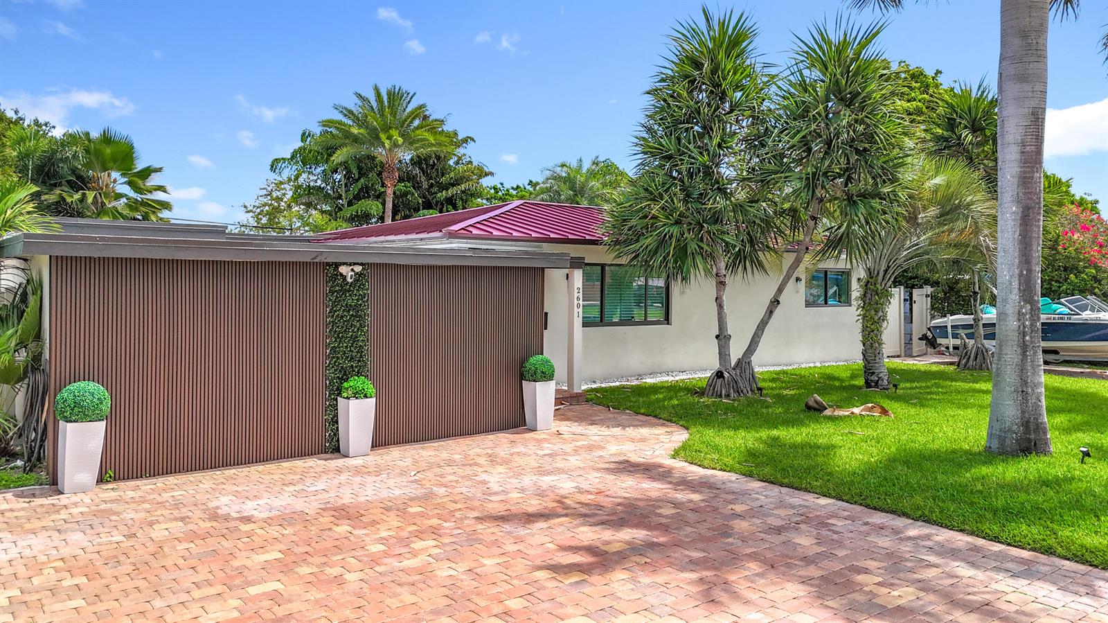 A single-story house with a red metal roof, vertical wood siding, and a brick driveway — 2601 NE 18th Street, Pompano Beach FL 33062, POMPANO BEACH, FL