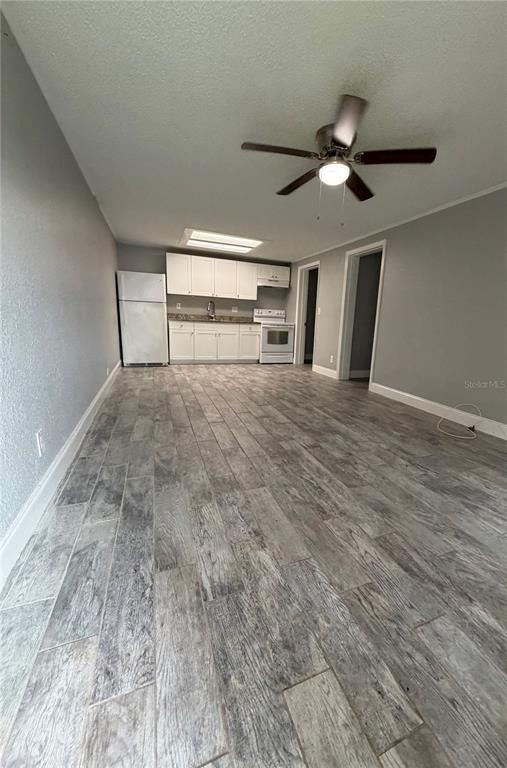 A kitchen with white cabinets and appliances opens into a living area with wood-look flooring — 1400 STRAWBERRY PLACE UNIT 33, PLANT CITY, FL
