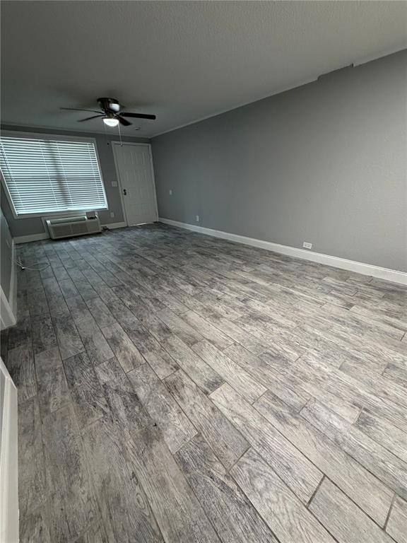An empty room features gray walls, wood-look tile flooring, a ceiling fan, and a window — 1400 STRAWBERRY PLACE UNIT 33, PLANT CITY, FL