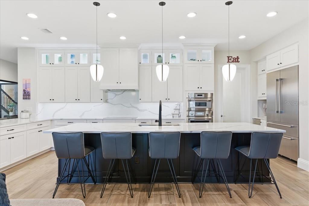 A modern kitchen features a large dark island with bar stools and white cabinetry — 10123 BUCKLOW HILL DRIVE, ORLANDO, FL