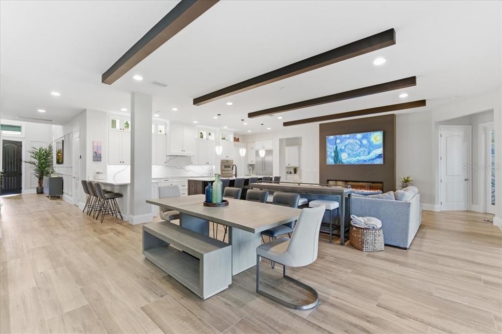 An open-concept kitchen and living area features wood-look tile flooring and exposed ceiling beams — 10123 BUCKLOW HILL DRIVE, ORLANDO, FL