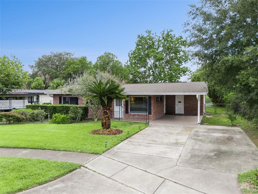 A single-story brick house features a concrete driveway, a front carport, and a palm tree — 812 AGNES DRIVE, ALTAMONTE SPRINGS, FL