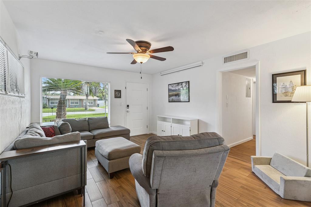 A living room features gray furniture, wood-look tile floors, a ceiling fan, and a window — 812 AGNES DRIVE, ALTAMONTE SPRINGS, FL