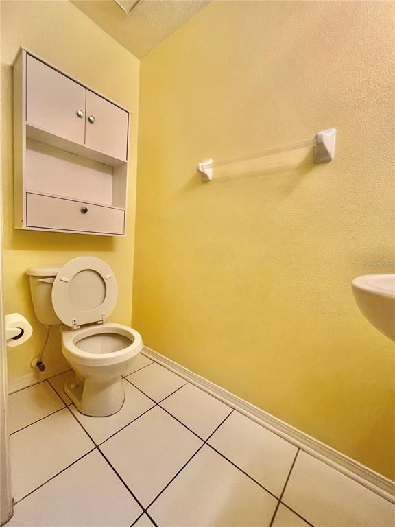 A bathroom features a white toilet, a wall-mounted cabinet, and a towel bar on yellow walls — 1211 KENNEWICK COURT, WESLEY CHAPEL, FL
