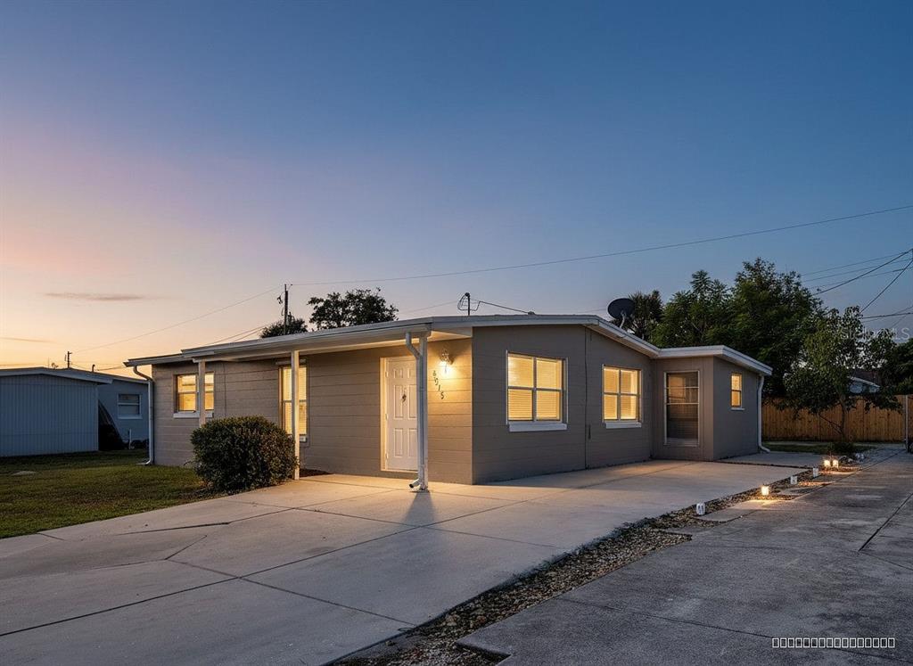 A single-story gray house with a concrete driveway and a covered front entryway at dusk — 8215 AGRESS AVENUE, NORTH PORT, FL