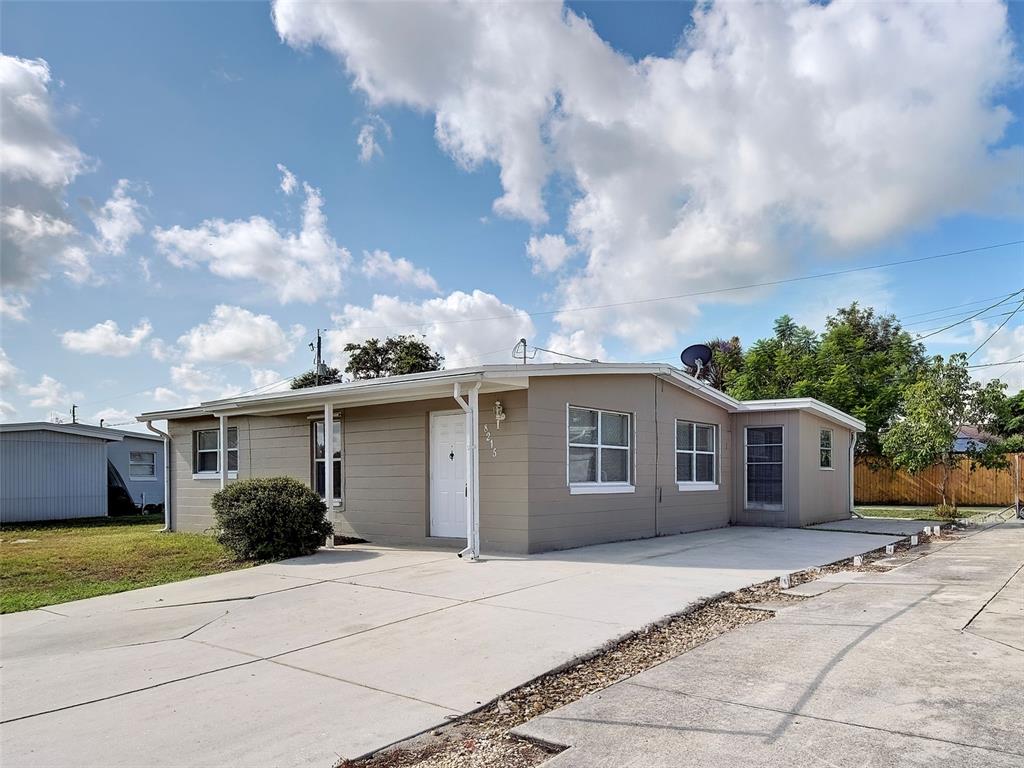 A tan, single-story house with a concrete driveway and a white front door — 8215 AGRESS AVENUE, NORTH PORT, FL