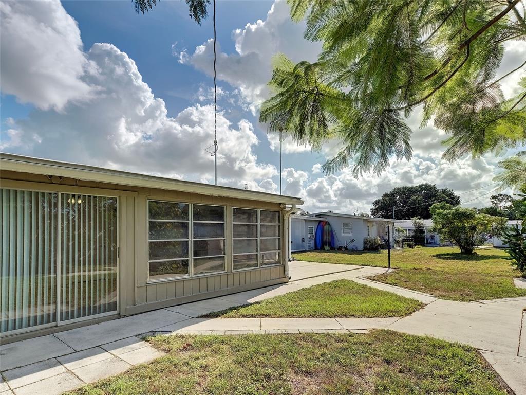 An exterior view of a house with a concrete patio and a large grassy yard — 8215 AGRESS AVENUE, NORTH PORT, FL