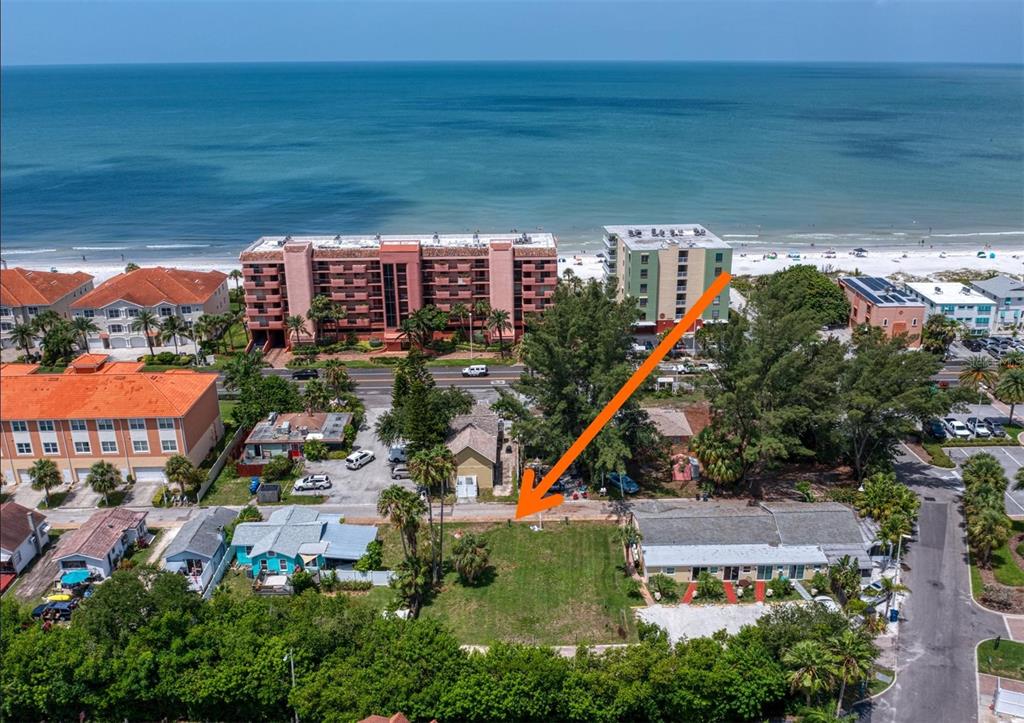 An aerial view shows a vacant rectangular lot situated between two houses near the beach — WHISPERING PINES DRIVE, INDIAN SHORES, FL