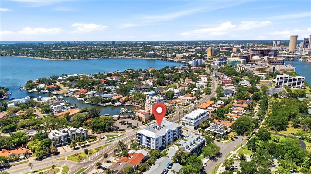 A four-story white apartment building with balconies and palm trees sits beside a paved road — 91 DAVIS BOULEVARD UNIT 303, TAMPA, FL