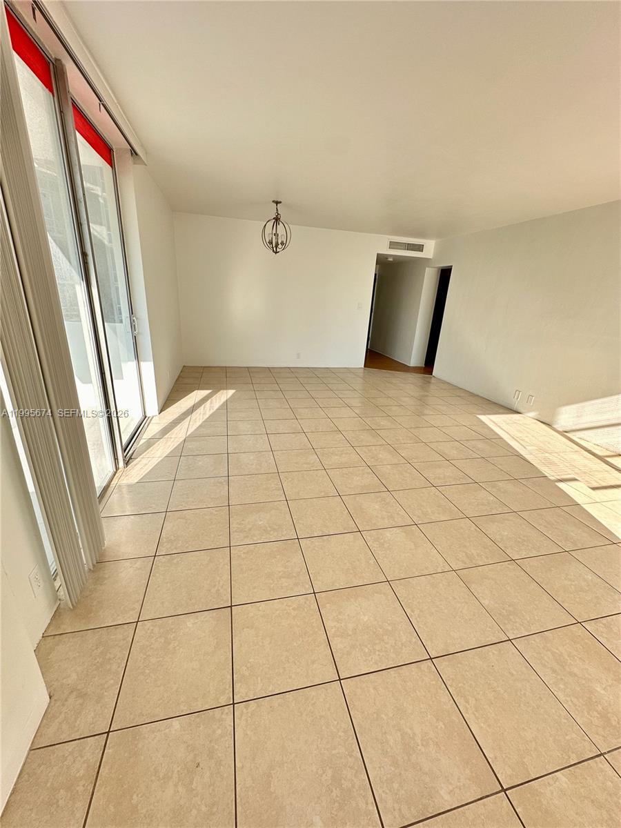An empty room features beige tile flooring, white walls, and a sliding glass door — 3301 NE 5th Ave # 618, Miami FL 33137, MIAMI, FL