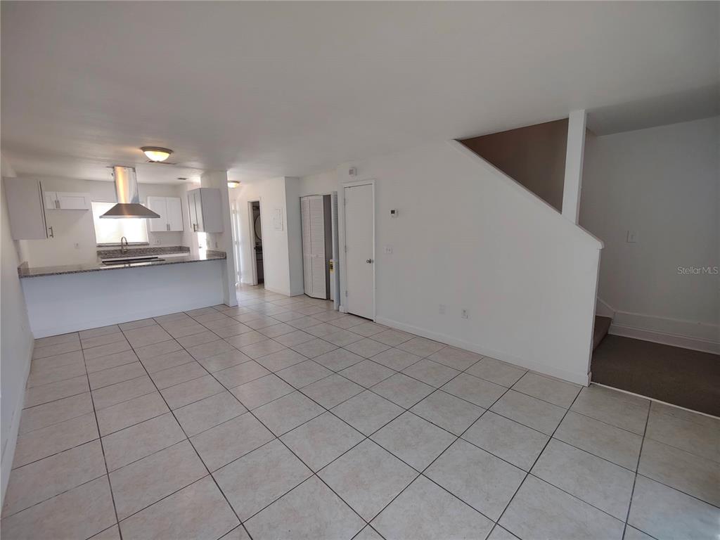 An open-concept living area features tiled floors, a kitchen with white cabinets, and a staircase — 5835 CURRY FORD ROAD, ORLANDO, FL