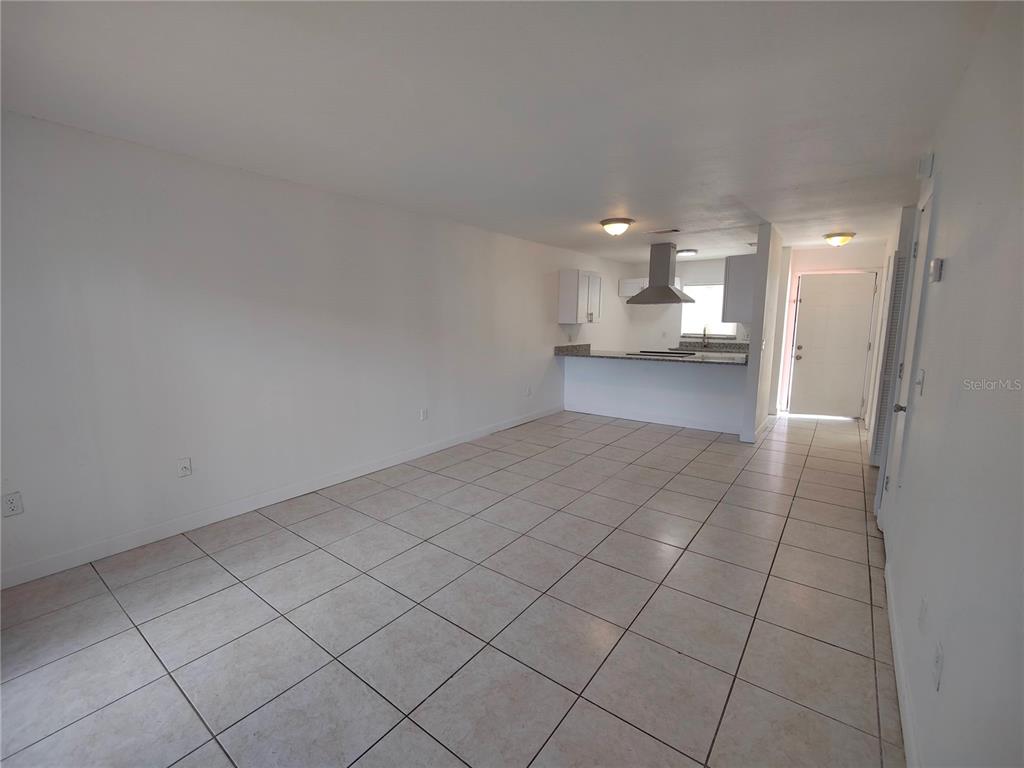 An open-concept living area features light-colored tile flooring and a kitchen with white cabinets — 5835 CURRY FORD ROAD, ORLANDO, FL
