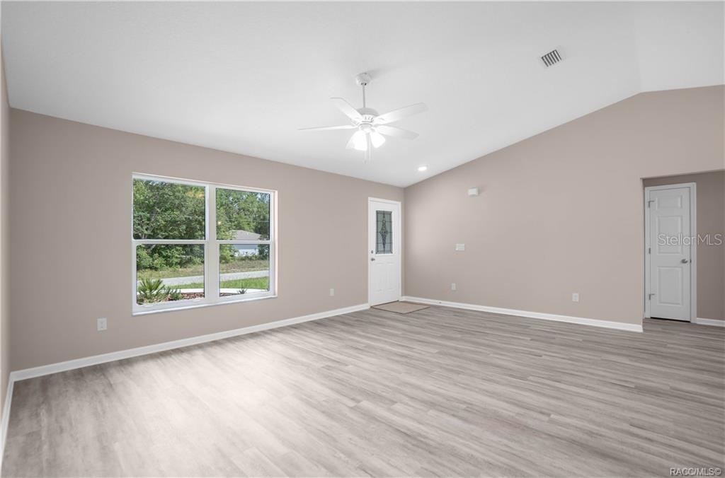 A living room with light gray wood-look flooring, a vaulted ceiling, and a ceiling fan — 8880 N CIRCULAR WAY, CITRUS SPRINGS, FL