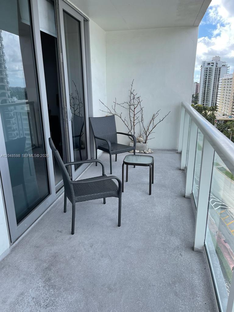 A balcony features two dark wicker chairs, a small side table, and a potted plant — 5701 Collins Ave # 1411, Miami Beach FL 33140, MIAMI BEACH, FL