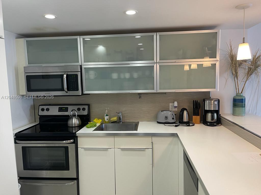 A kitchen features white cabinets, stainless steel appliances, and a light-colored countertop — 5701 Collins Ave # 1411, Miami Beach FL 33140, MIAMI BEACH, FL