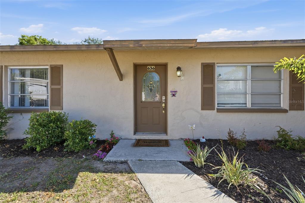A tan house exterior features a brown front door with a decorative glass insert — 636 TESSIER COURT, TARPON SPRINGS, FL