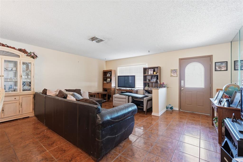 A living room features brown tile floors, a dark leather sofa, and a front entry door — 636 TESSIER COURT, TARPON SPRINGS, FL