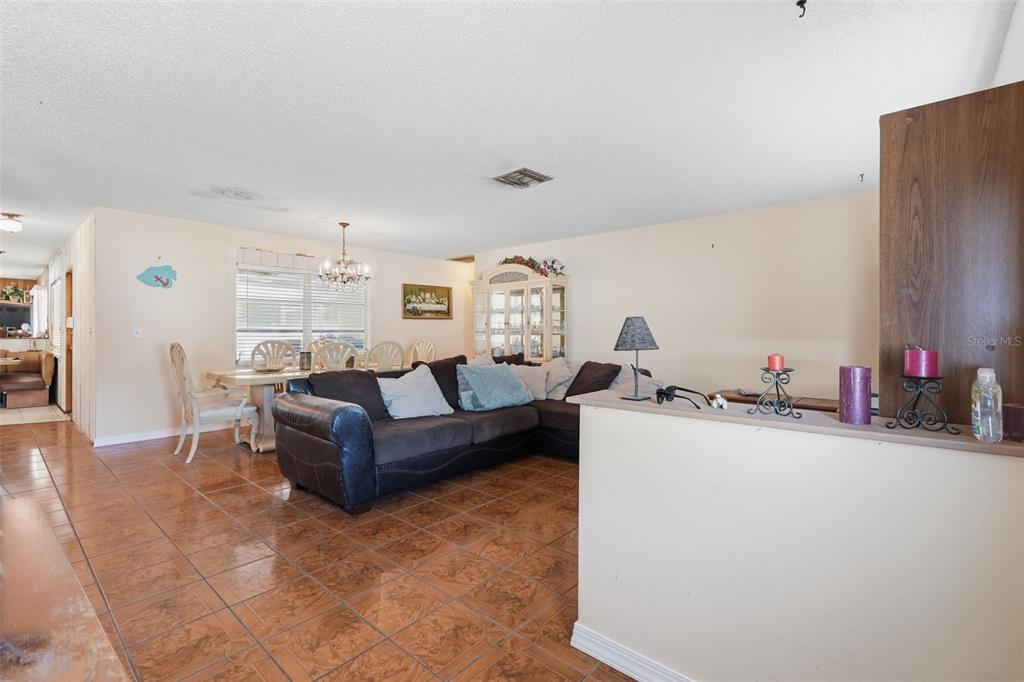 A living and dining area features brown tile flooring, a dark sofa, and a hutch — 636 TESSIER COURT, TARPON SPRINGS, FL