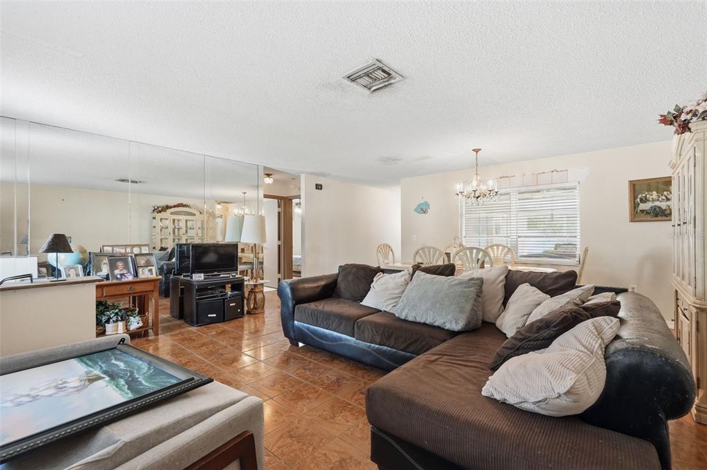 A living room features a brown sectional sofa, tiled floors, and a mirrored wall — 636 TESSIER COURT, TARPON SPRINGS, FL