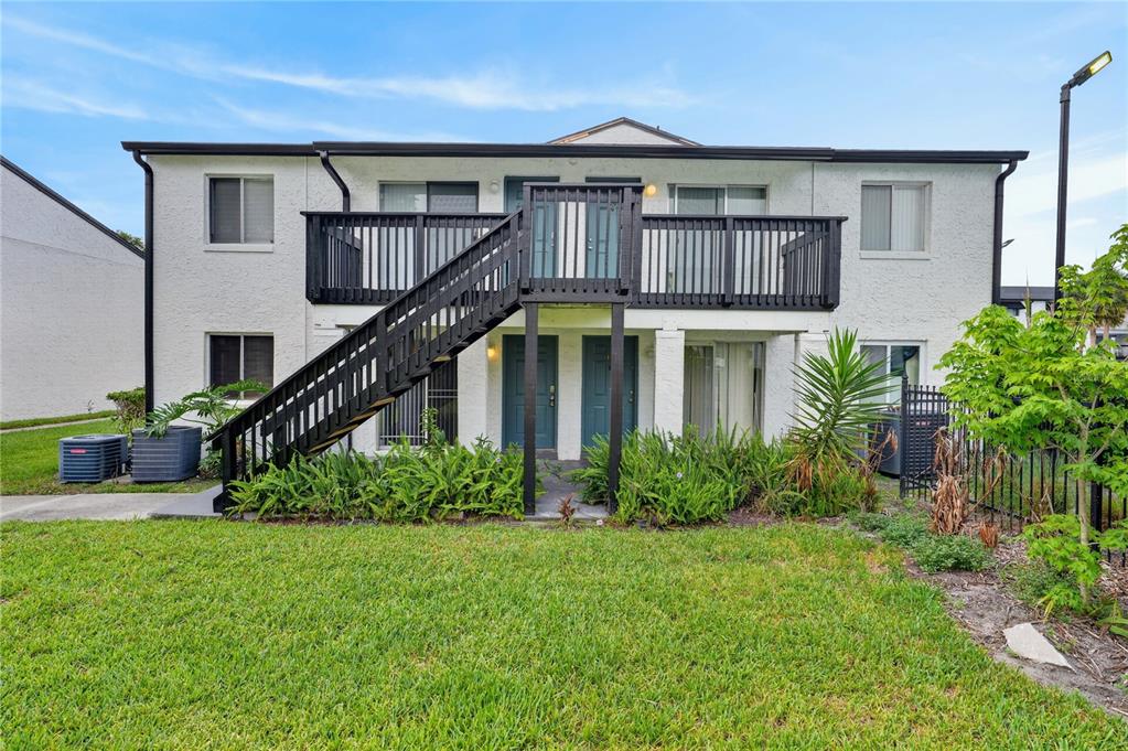 A two-story apartment building features a wooden exterior staircase leading to an upper balcony — 4205 S. SEMORAN BLVD UNIT 11, ORLANDO, FL
