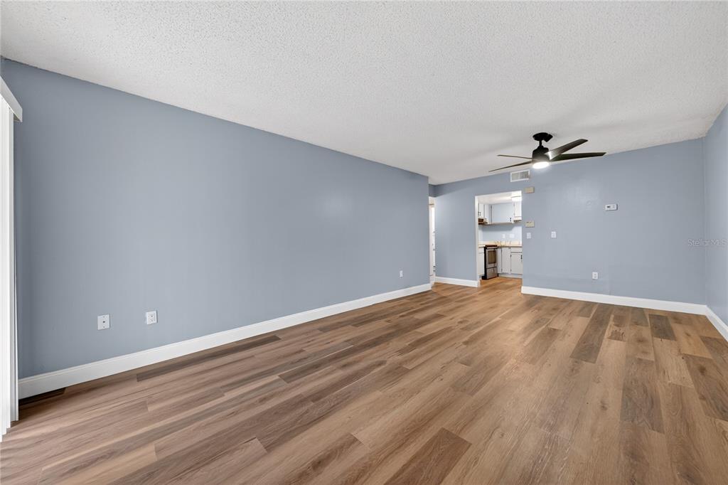 An empty room with light blue walls, wood-look flooring, and a ceiling fan — 4205 S. SEMORAN BLVD UNIT 11, ORLANDO, FL