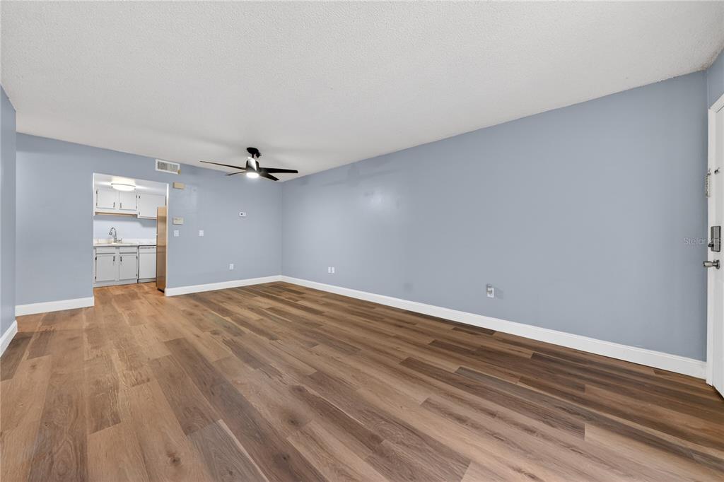 A living room with light blue walls, wood-look flooring, and a ceiling fan — 4205 S. SEMORAN BLVD UNIT 11, ORLANDO, FL