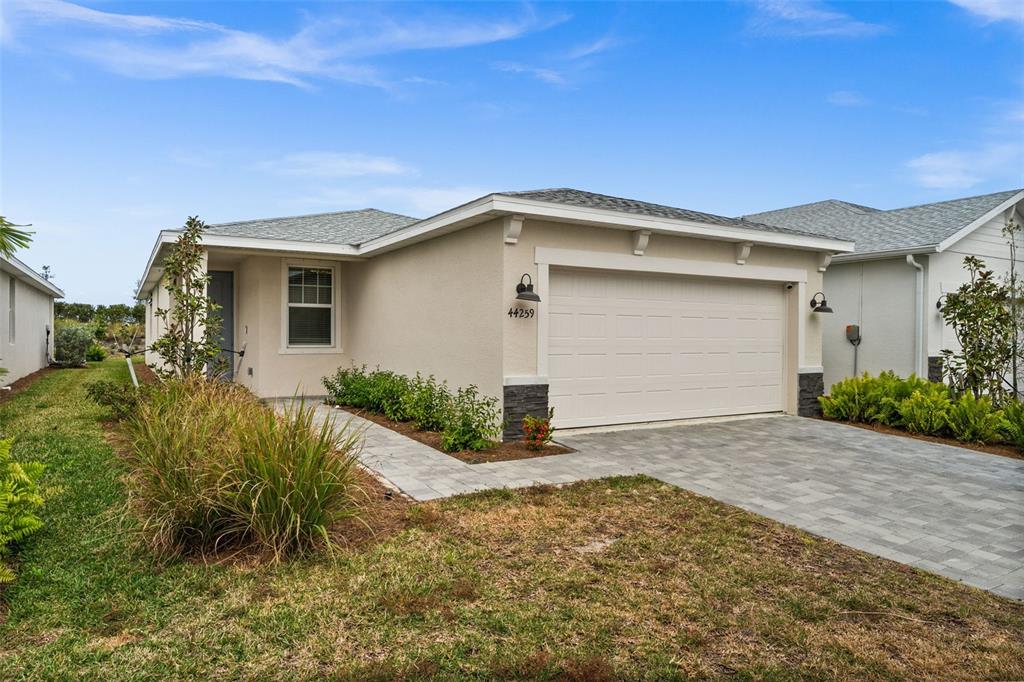A single-story house with a beige stucco exterior, a two-car garage, and a paved driveway — 44259 SADDLEWOOD COURT, PUNTA GORDA, FL