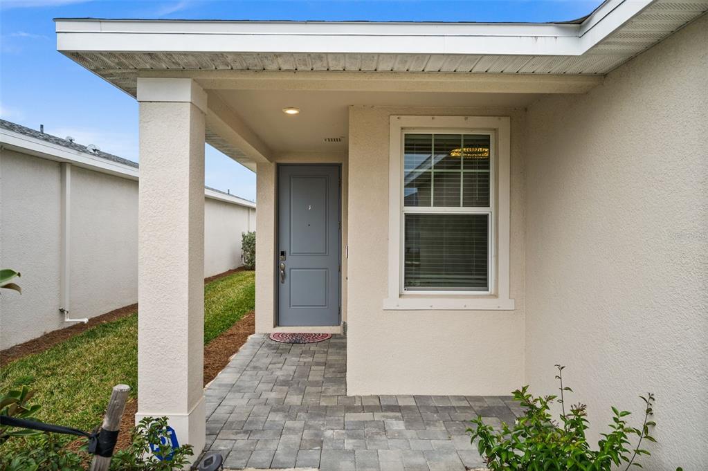 A covered entryway features a gray front door, a paver walkway, and a single window — 44259 SADDLEWOOD COURT, PUNTA GORDA, FL