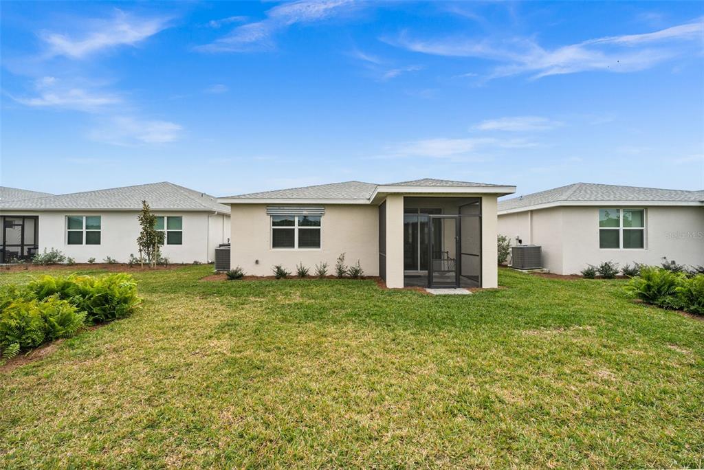 The rear exterior of a single-story house features a screened-in patio and a grassy yard — 44259 SADDLEWOOD COURT, PUNTA GORDA, FL