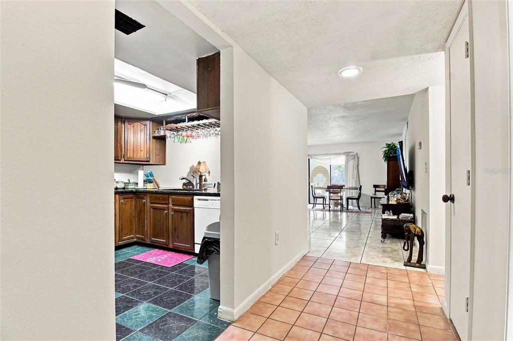 A view from a tiled hallway looking into a kitchen with wood cabinets and dining area — 7104 KIRSCH COURT UNIT 3, NEW PORT RICHEY, FL