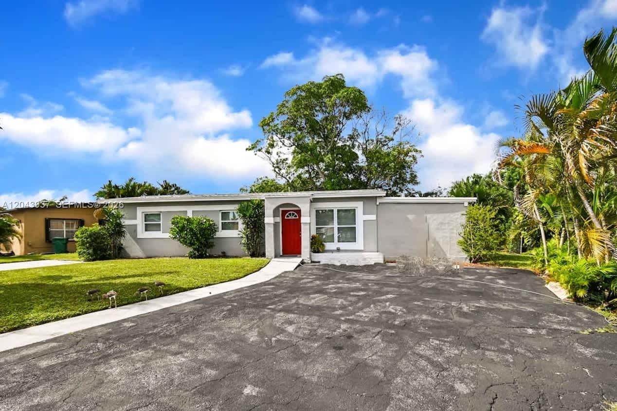 A single-story house with a red front door and a paved driveway under a blue sky — DELRAY BEACH, FL